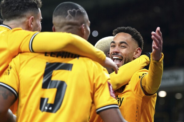 Wolverhampton Wanderers' Matheus Cunha, right, celebrates scoring their side's third goal of the game from the penalty spot with teammates in extra time during the English FA Cup third round replay soccer match between Wolverhampton Wanderers and Brentford at the Molineux Stadium, Wolverhampton, England, Tuesday, Jan. 16, 2024. (Jacob King/PA via AP)