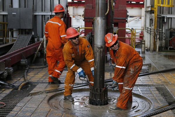 FILE - Pemex oil workers set the drill on the Centenario deep-water drilling platform in the Gulf of Mexico off the coast of Veracruz, Mexico, Nov. 22, 2013. The 1938 nationalization of Mexico's oil sector from U.S. and British companies is a point of pride for millions of Mexicans.(AP Photo/Dario Lopez-Mills, File)