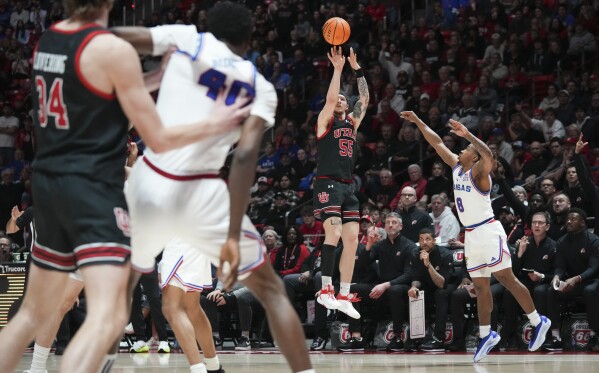 Utah guard Gabe Madsen (55) shoots a 3-pointer, breaking Utah's all time 3 point record, as Kansas guard David Coit (8) defends during the second half of an NCAA college basketball game, Saturday, Feb. 15, 2025, in Salt Lake City. (AP Photo/Bethany Baker)