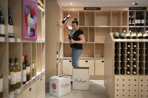 An employee removes American-made wine from their shelves at Bishop's Cellar in Halifax on Wednesday, March 5, 2025. (Darren Calabrese /The Canadian Press via AP)