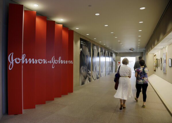 FILE - In this July 30, 2013, file photo, people walk along a corridor at the headquarters of Johnson & Johnson in New Brunswick, N.J. Johnson & Johnson's long-awaited vaccine appears to protect against COVID-19 with just one shot – not as strong as some two-shot rivals but still potentially helpful for a world in dire need of more doses. (AP Photo/Mel Evans, File)