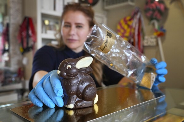 Niaz Mardan wraps a luxury handmade Belgian chocolate rabbit at Sandrine a chocolate shop in south west London, Thursday, March 21, 2024. Niaz Mardan, is suffering due to high cocoa prices, she's making no profits and fears she will have to close the shop that's been around for 25 years (she's the third owner and took over in 2019). (AP Photo/Kirsty Wigglesworth)