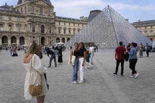 FILE - Tourists take pictures in front of the Pyramide in the Louvre Museum courtyard, in Paris, France, Monday, June 20, 2022. Tourism came back with a vengeance to France this summer, sending revenues over pre-pandemic levels, according to preliminary government estimates released this week. Crowds packed Paris landmarks and Riviera beaches, notably thanks to an influx of Americans benefiting from the weak euro, but also British and other European visitors reveling in the end of pandemic restrictions. (AP Photo/Francois Mori, File)