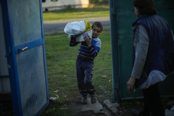 A young boy carries a bag with food given by Ukrainian volunteers in recently retaken Pidlyman village, east Ukraine, Friday, Oct. 7, 2022. (AP Photo/Francisco Seco)