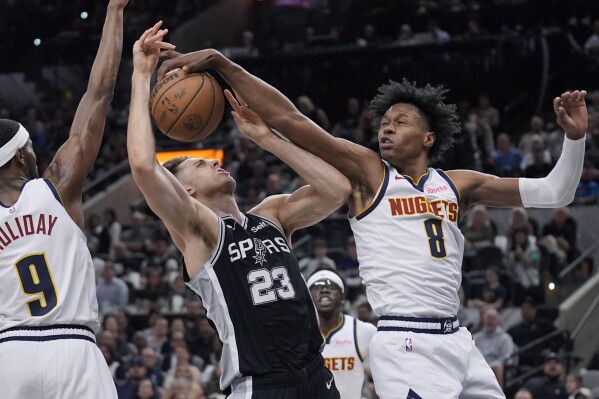 San Antonio Spurs forward Zach Collins (23) is blocked by Denver Nuggets forward Peyton Watson (8) during the second half of an NBA basketball game in San Antonio, Friday, April 12, 2024. (AP Photo/Eric Gay)