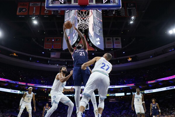 Philadelphia 76ers' Joel Embiid, center, goes up for a shot against Minnesota Timberwolves' Rudy Gobert, right, and Karl-Anthony Towns during the first half of an NBA basketball game, Wednesday, Dec. 20, 2023, in Philadelphia. (AP Photo/Matt Slocum)