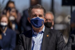 Virginia Gov. Ralph Northam attends a news conference to announce the expansion of commuter rail in Virginia at the Amtrak and Virginia Railway Express (VRE) Alexandria Station, Tuesday, March 30, 2021, in Alexandria, Va. (AP Photo/Andrew Harnik)