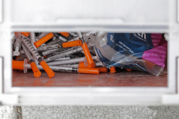 FILE - A box of needles collected at a homeless encampment at Ballard Commons Park is shown on May 4, 2020, in Seattle. Seattle Mayor Bruce Harrell is asking members of the city council who recently voted against adopting the state's controlled substance law to consider an amended plan. Harrell on Monday, July 31, 2023, offered a proposal that would align the city's code with new state law, making possession and public use of drugs such as fentanyl a gross misdemeanor. (AP Photo/Ted S. Warren, File)