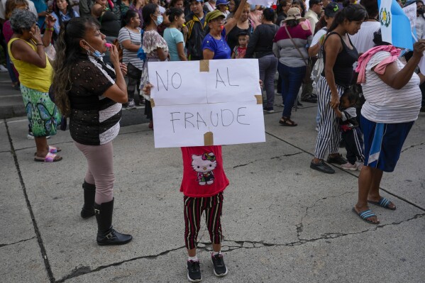 A child holds a poster with a message that reads in Spanish: 