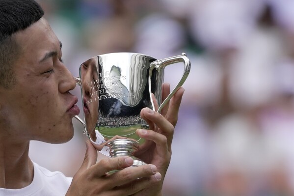 Japan's Tokito Oda celebrates with the trophy after beating Britain's Alfie Hewitt to win the final of the men's wheelchair singles on day fourteen of the Wimbledon tennis championships in London, Sunday, July 16, 2023. (AP Photo/Kin Cheung)