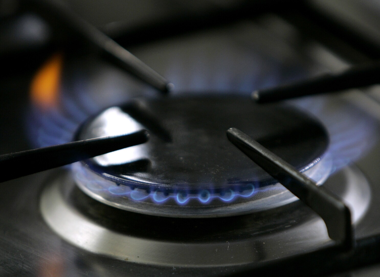 Una imagen bien enfocada que captura las intensas llamas azules de un  quemador de estufa de gas propano en una cocina hogareña