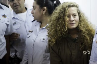 FILE - In this Dec. 28, 2017 file photo, Ahed Tamimi is brought to a courtroom inside Ofer military prison near Jerusalem. A senior Israeli official on Wednesday said he led a secret investigation into 16-year-old Palestinian protest icon Ahed Tamimi and her family, in part because their appearance, including "blond-haired, freckled" children in “Western clothes,” made them seem less like “real” Palestinians. (AP Photo/Mahmoud Illean, File)