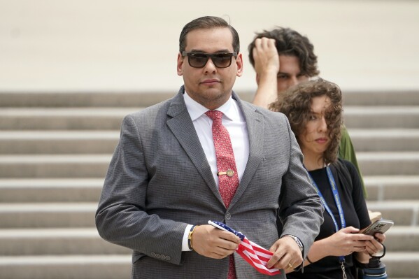 FILE - U.S. Rep. George Santos, R-N.Y., holds a miniature American flag that was presented to him as he departs federal court, Friday, June 30, 2023, in Central Islip, N.Y. Sam Miele, a former political fundraiser for Santos, was arrested Wednesday, Aug. 16, on federal charges of wire fraud and aggravated identity theft as part of an alleged scheme to trick donors into giving money to Santos under a false name. (AP Photo/John Minchillo, File)