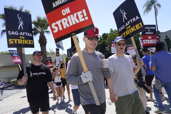 Actor Bob Odenkirk, center, carries a sign on a picket line outside Paramount studios on Wednesday, July 19, 2023, in Los Angeles. The actors strike comes more than two months after screenwriters began striking in their bid to get better pay and working conditions. (AP Photo/Chris Pizzello)