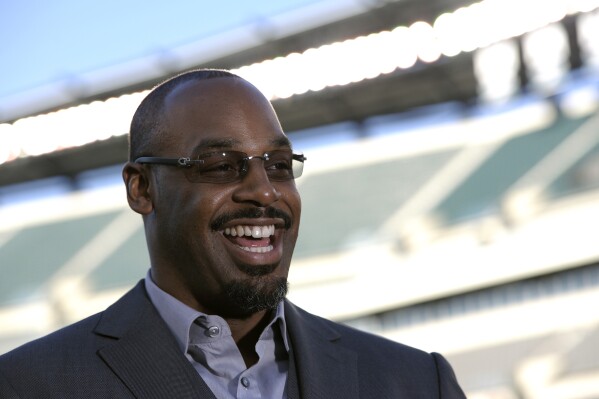 FILE - Former Philadelphia Eagles quarterback Donovan McNabb laughs during an interview before an NFL football game between the Eagles and the Kansas City Chiefs, Sept. 19, 2013, in Philadelphia. McNabb will host a video podcast twice a week on OutKick. Tuesday, Sept. 19, 2023, marked the debut of “The 5 Spot with Donovan McNabb.” (AP Photo/Michael Perez, File)