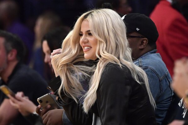 FILE - In this Jan. 13, 2019, file photo, Khloe Kardashian watches during the second half of an NBA basketball game between the Los Angeles Lakers and the Cleveland Cavaliers in Los Angeles. Kardashian says she had tested positive for the coronavirus.  The reality star confirmed her previous diagnosis in a Wednesday, Oct. 28, 2020, sneak peek clip of “Keeping Up with the Kardashians.” The bedridden Kardashian spoke in the video with a hoarse voice.  (AP Photo/Mark J. Terrill, File)