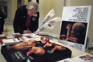 FILE - Lyn Toelle fills out forms before bringing roses to her legislators during the Rose Day observance, an anti-abortion event, at the state capitol in Oklahoma City on Feb. 4, 2004. Two abortion providers in Oklahoma said Tuesday they're continuing to be inundated with women from Texas seeking to terminate their pregnancies after Texas last year passed the most restrictive anti-abortion law in the U.S. in decades. (AP Photo/Jeffrey Haderthauer, File)