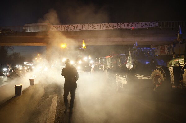 Farmers occupy a highway near Ableiges, north of Paris, Friday, Jan. 26, 2024. Protesting farmers shut down long stretches of some of France's major motorways on Friday, using their tractors to block and slow traffic and squeeze the government ever more tightly to cede to their demands that growing and rearing food should be made easier and more lucrative. Banner reads: no farming, no food. (AP Photo/Thomas Padilla)