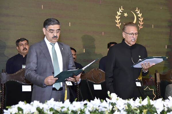 In this photo released by Pakistan's President Office, President Arif Alvi, right, administrates oath from Anwaar-ul-Haq Kakar as caretaker Prime Minister during a ceremony, in Islamabad, Pakistan, Monday, Aug. 14, 2023. Kakar was sworn in as the country's prime minister to head a caretaker national government that will oversee parliamentary elections amid one of the worst economic crises the Islamic nation has faced, officials said. (Pakistan President Office vis AP)