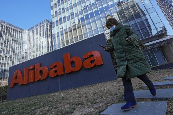 A woman wearing a face mask run past the offices of Chinese e-commerce firm Alibaba in Beijing on Dec. 13, 2021. A former employee of Chinese e-commerce giant Alibaba says human resources and upper management wouldn’t deal with her accusation of sexual assault. So she went into the busy cafeteria at the headquarters of the Chinese e-commerce giant and screamed out her plight. Now she is paying the price. The company fired her. (AP Photo/Andy Wong)