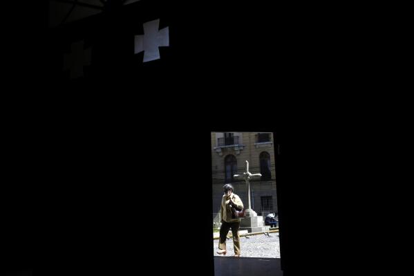 A woman, framed by a doorway of the Merced Catholic Church, walks past in La Paz, Bolivia, Tuesday, May 2, 2023. Bolivia’s Jesuit congregation has apologized publicly and is launching an investigation into a late Spanish priest who allegedly abused several minors in Bolivia dating back to the 1980s. (AP Photo/Juan Karita)
