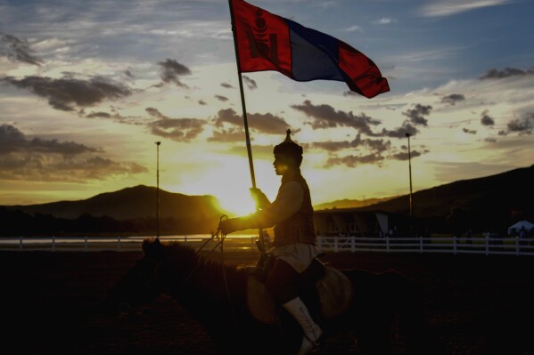 A horse rider holds a Mongolian flag during a traditional performance at a cultural event organized for the media and entourage following Pope Francis' visit to Mongolia, at the Mongolia Cultural Park, some 40 kilometers out of Ulaanbaatar, Mongolia, Friday, Sept. 1, 2023. (AP Photo/Andrew Medichini)