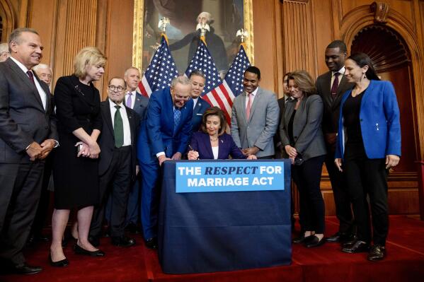 House Speaker Nancy Pelosi of Calif., accompanied by Senate Majority Leader Sen. Chuck Schumer of N.Y., left, and other members of Congress, signs the H.R. 8404, the Respect For Marriage Act, on Capitol Hill in Washington, Thursday, Dec. 8, 2022. (AP Photo/Andrew Harnik)