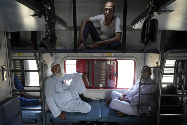 Haji Abdul Subhan, left, and Santosh Kumar Aggarwal, top, travel in a non air-conditioned sleeper compartment of the Thirukkural Express, India, Saturday, April 20, 2024. (ĢӰԺ Photo/Manish Swarup)