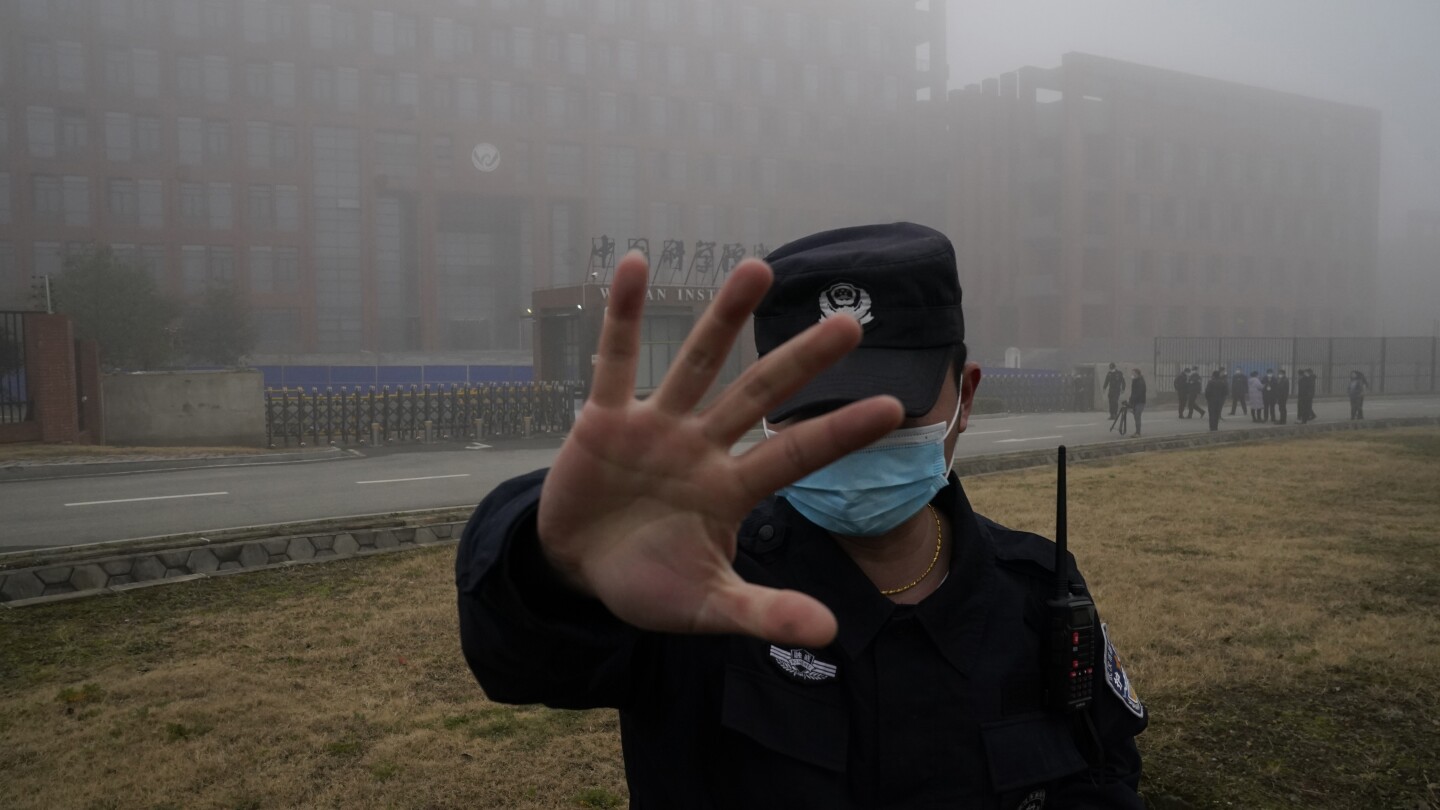 FILE - A security person moves journalists away from the Wuhan Institute of Virology after a World Health Organization team arrived for a field visit 