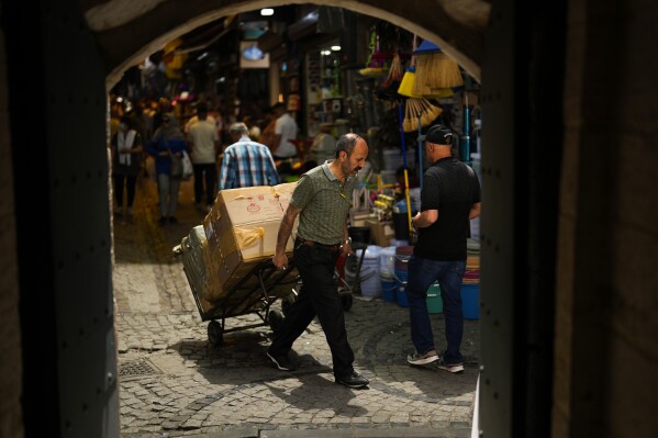 A man pulls a trolley with goods in a street market in Eminonu commercial district in Istanbul, Turkey, Friday, June 16, 2023. The Turkish central bank faces a key test Thursday June 22, 2023, on turning to more conventional economic policies to counter sky-high inflation after newly reelected President Recep Tayyip Erdogan gave mixed signals about an approach that many blame for worsening a cost-of-living crisis. (AP Photo/Francisco Seco)