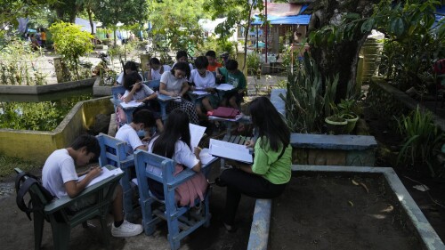 Los estudiantes enseñan bajo los árboles cuando la escuela se convirtió en un centro de evacuación temporal en la ciudad de Malilipot, provincia de Albay, en el noreste de Filipinas, el jueves 15 de junio de 2023. Miles de residentes han dejado comunidades agrícolas empobrecidas en un área de 6 kilómetros (3,7 millas). ) del cráter Mayon en evacuaciones forzadas desde que aumentó la actividad volcánica la semana pasada.  (Foto AP/Aarón Favila)