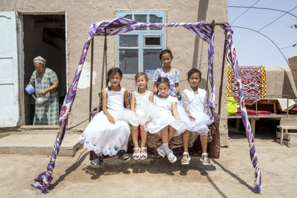 Girls pose for a photo at a house in Aralsk village, next to the disappearing Aral Sea, near Muynak, Uzbekistan, Tuesday, July 11, 2023. (AP Photo/Ebrahim Noroozi)