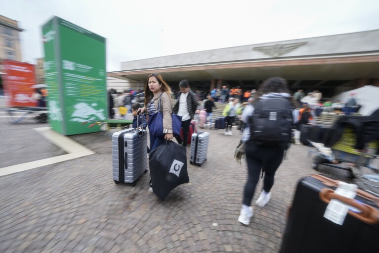 Tourists arrive at the main train station in Venice, Italy, Wednesday, April 24, 2024. The lagoon city of Venice begins a pilot program Thursday, April 25, 2024 to charge daytrippers a 5 euro entry fee that authorities hope will discourage tourists from arriving on peak days. Officials expect some 10,000 people will pay the fee to access the city on the first day, downloading a QR code to prove their payment. (AP Photo/Luca Bruno)