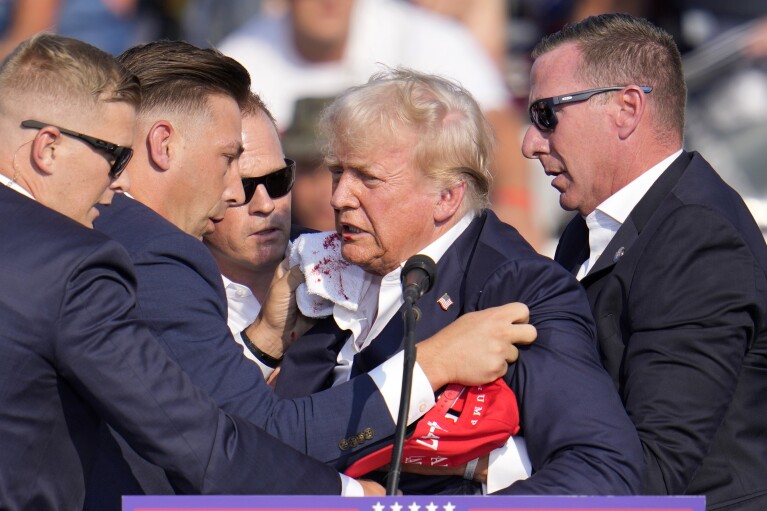 Republican presidential candidate former President Donald Trump is helped off the stage at a campaign event in Butler, Pa., on Saturday, July 13, 2024. (AP Photo/Gene J. Puskar)