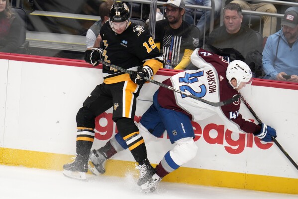 Pittsburgh Penguins' Reilly Smith (19) collides with Colorado Avalanche's Josh Manson along the boards during the third period of an NHL hockey game in Pittsburgh, Thursday, Oct. 26, 2023. (AP Photo/Gene J. Puskar)