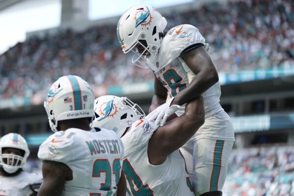 Miami Dolphins defensive tackle Christian Wilkins (94) lifts running back De'Von Achane (28) after Achane scored a touchdown during the second half of an NFL football game against the Denver Broncos, Sunday, Sept. 24, 2023, in Miami Gardens, Fla. The Dolphins defeated the Broncos 70-20. (AP Photo/Rebecca Blackwell)