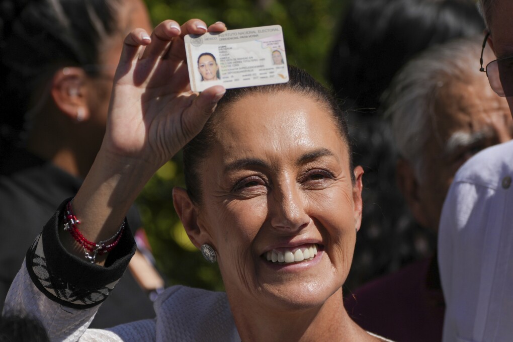 Ruling party presidential candidate Claudia Sheinbaum shows her ID as she leaves a polling station where she voted during general elections in Mexico City, Sunday, June 2, 2024. Mexico’s next president and its first female leader in more than 200 years of independence, Sheinbaum captured the post by promising continuity, emerging victorious early Monday. (AP Photo/Marco Ugarte)