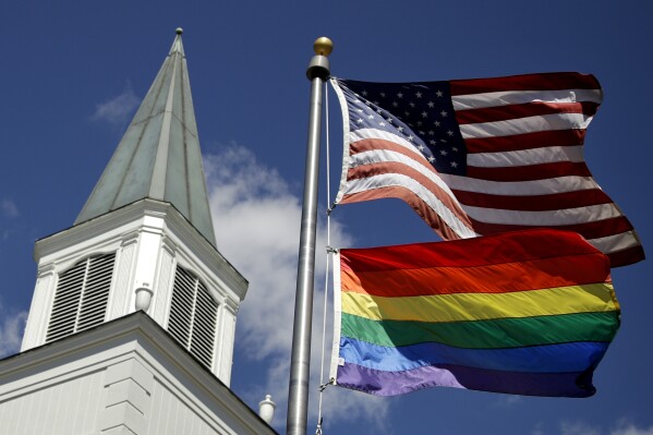 FILE - A gay pride rainbow flag flies along with the U.S. flag in front of the Asbury United Methodist Church in Prairie Village, Kan., on April 19, 2019. A quarter of U.S. congregations in the United Methodist Church have received permission to leave the denomination during a five-year window, closing in December 2023, that authorized departures for congregations over disputes involving the church's LGBTQ-related policies. (AP Photo/Charlie Riedel, File)