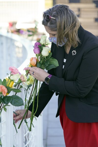 Crissy Sokol places a flower at the Space Mirror Memorial during a ceremony to honor fallen astronauts at the at the Kennedy Space Center Visitors Complex, Thursday, Jan. 28, 2021, in Cape Canaveral, Fla. (AP Photo/John Raoux)