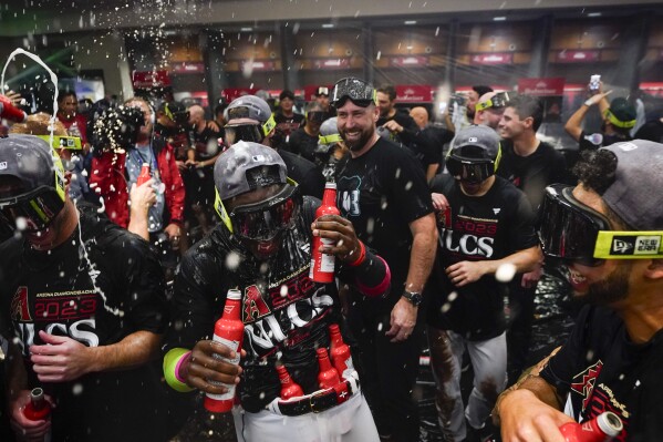 Arizona Diamondbacks' Geraldo Perdomo, center, celebrates with teammates after the Diamondbacks defeated the Los Angeles Dodgers 4-2 in Game 3 to win a baseball NL Division Series, Wednesday, Oct. 11, 2023, in Phoenix. (AP Photo/Ross D. Franklin)