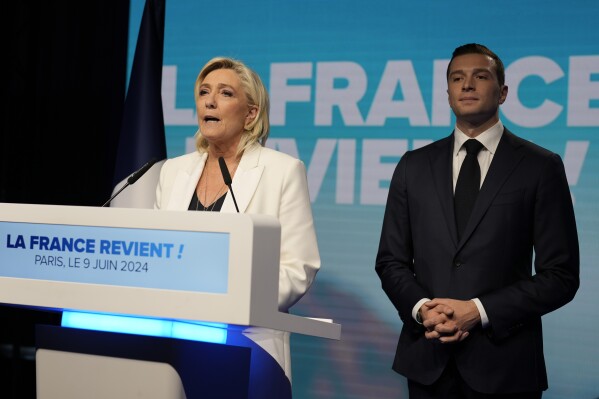 French far-right leader Marine Le Pen delivers a speech as Jordan Bardella, president of the French far-right National Rally, listens at the party election night headquarters after French President Emanuel Macron announced he dissolves National Assembly and calls new legislative election after defeat in EU vote, Sunday, June 9, 2024 in Paris. First projected results from France put far-right National Rally party well ahead in EU elections, according to French opinion poll institutes. (AP Photo/Lewis Joly)