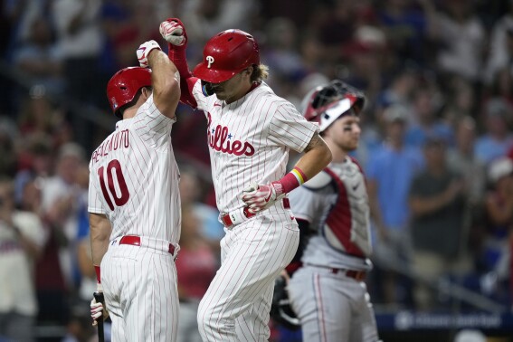 Philadelphia Phillies' Bryson Stott, center, celebrates with J.T. Realmuto, left, after hitting a home run against Minnesota Twins pitcher Brent Headrick during the sixth inning of a baseball game, Friday, Aug. 11, 2023, in Philadelphia. (AP Photo/Matt Slocum)