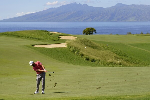 FILE- Jon Rahm, of Spain, hits from the 13th fairway during the final round of the Tournament of Champions golf event, Sunday, Jan. 9, 2022, at Kapalua Plantation Course in Kapalua, Hawaii. The PGA Tour say the tournament will return to Kapalua on Maui five months after the deadly wildfires. (AP Photo/Matt York, File)