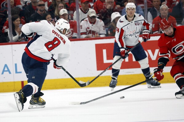 Washington Capitals' Alex Ovechkin (8) shoots the puck past Carolina Hurricanes Dmitry Orlov (7) for a goal during the second period of an NHL hockey game in Raleigh, N.C., Wednesday, April 2, 2025. (AP Photo/Karl DeBlaker)