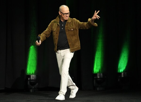 Michael Keaton, a cast member in the upcoming film "Beetlejuice Beetlejuice," waves to the audience as he arrives onstage for the Warner Bros. Pictures presentation at CinemaCon 2024, Tuesday, April 9, 2024, in Las Vegas. (AP Photo/Chris Pizzello)