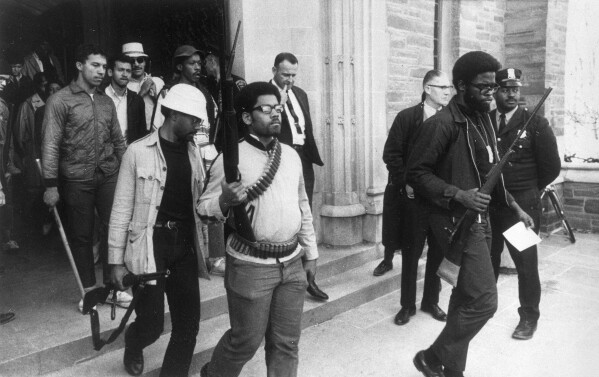 FILE - Heavily armed African American students leave Straight Hall at Cornell University in Ithaca, N.Y., on April 20, 1969, after barricading themselves in the building led by Ed Whitfield, far right, demanding a degree-granting African American Studies program. The image won the 1970 Pulitzer Prize for spot news photography. Hal Buell, who led The Associated Press' photo operations from the darkroom era into the age of digital photography over a four-decade career with the news organization that included 12 Pulitzer Prizes and some of the defining images of the Vietnam War, has died. He was 92. (AP Photo/Steve Starr, File)