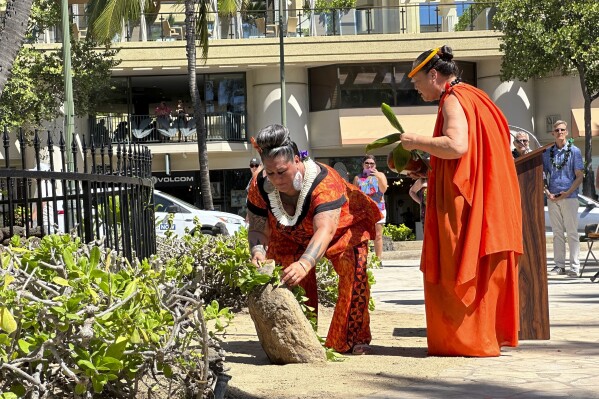 Hinaleimoana Wong-Kalu, left, and Charlani Kalama, both kumu, or master teachers, participate in a blessing ceremony for a new plaque for the Kapaemahu stones in Honolulu on Tuesday, Oct. 24, 2023. Honolulu officials introduced a new interpretive plaque for four large boulders in the center of Waikiki that honor Taihitian healers of dual male and female spirit who visited Oahu some 500 years ago. (AP Photo/Audrey McAvoy)