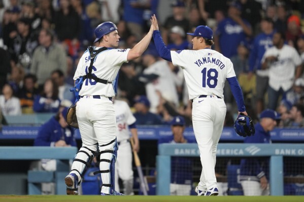 Los Angeles Dodgers catcher Will Smith (16) celebrates with starting pitcher Yoshinobu Yamamoto (18) as they walk back to the dugout during the sixth inning of a baseball game against the Colorado Rockies in Los Angeles, Saturday, June 1, 2024. (AP Photo/Ashley Landis)