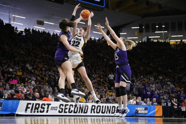 Iowa guard Caitlin Clark (22) drives to the basket as she is double-teamed by Holy Cross guards Kaitlyn Flanagan (5) and Bronagh Power-Cassidy (13) in the second half of a first-round college basketball game in the NCAA Tournament, Saturday, March 23, 2024, in Iowa City, Iowa. Iowa won 91-65. (AP Photo/Matthew Putney)