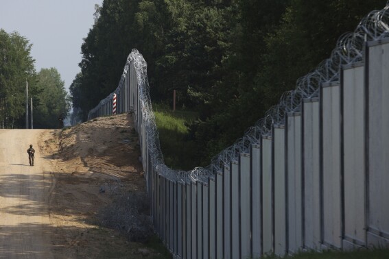 FILE - A Polish border guard patrols the area of a built metal wall on the border between Poland and Belarus, near Kuznice, Poland, on June 30, 2022. Security of the European Union's border with Russia’s ally Belarus is Polish government’s top priority, Poland’s chief politician Jaroslaw Kaczynski said Thursday, July 27, 2023. Deputy prime minister and conservative ruling party leader, Kaczynski paid a visit to the village of Koden, on the EU nation’s border with Belarus. Later in the day Defense Minister Mariusz Blaszczak was to meet troops guarding the border. (AP Photo/Michal Dyjuk, File)